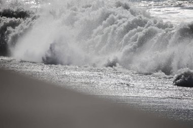 Tazacorte 'deki siyah kumlu sahilin dramatik geniş açılı görüntüsü. Turkuaz dalgalar kırılıyor. La Palma 'nın volkanik kıyı şeridi kasvetli, bulutlu gökyüzünün altında dalgalı su blokları var.