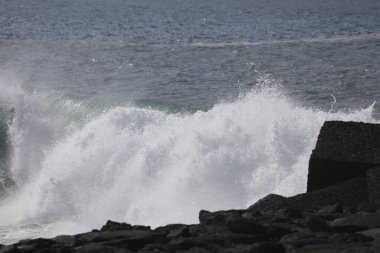 Şiddetli Atlantik dalgaları taş merdivenlere ve Tazacorte limanının dalgalanan sularına çarpıyor. La Palma kıyısındaki karanlık volkanik kayaların üzerine yüksek su püskürtüsü ve köpük..