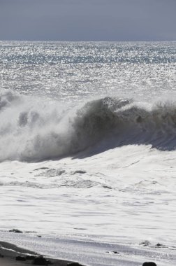 Büyük bir Atlantik dalgası Tazacorte sahiline çarpıyor. Beyaz köpük ve spreyle kırılan turkuaz suyun yakın çekimi denizin evcilleştirilmemiş gücünü gösteriyor. La Palma, Kanarya Adaları, İspanya