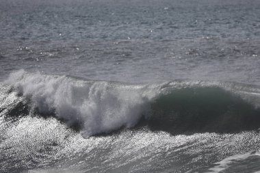 Büyük bir Atlantik dalgası Tazacorte sahiline çarpıyor. Beyaz köpük ve spreyle kırılan turkuaz suyun yakın çekimi denizin evcilleştirilmemiş gücünü gösteriyor. La Palma, Kanarya Adaları, İspanya