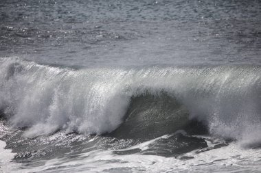 Büyük bir Atlantik dalgası Tazacorte sahiline çarpıyor. Beyaz köpük ve spreyle kırılan turkuaz suyun yakın çekimi denizin evcilleştirilmemiş gücünü gösteriyor. La Palma, Kanarya Adaları, İspanya