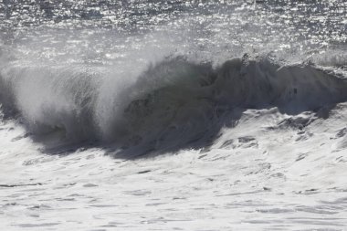 Büyük bir Atlantik dalgası Tazacorte sahiline çarpıyor. Beyaz köpük ve spreyle kırılan turkuaz suyun yakın çekimi denizin evcilleştirilmemiş gücünü gösteriyor. La Palma, Kanarya Adaları, İspanya