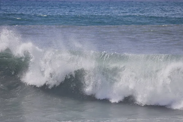 Büyük bir Atlantik dalgası Tazacorte sahiline çarpıyor. Beyaz köpük ve spreyle kırılan turkuaz suyun yakın çekimi denizin evcilleştirilmemiş gücünü gösteriyor. La Palma, Kanarya Adaları, İspanya