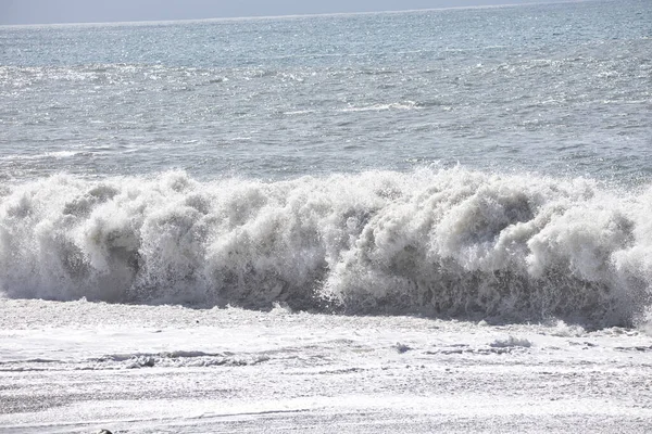 Büyük bir Atlantik dalgası Tazacorte sahiline çarpıyor. Beyaz köpük ve spreyle kırılan turkuaz suyun yakın çekimi denizin evcilleştirilmemiş gücünü gösteriyor. La Palma, Kanarya Adaları, İspanya