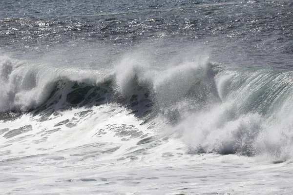 Büyük bir Atlantik dalgası Tazacorte sahiline çarpıyor. Beyaz köpük ve spreyle kırılan turkuaz suyun yakın çekimi denizin evcilleştirilmemiş gücünü gösteriyor. La Palma, Kanarya Adaları, İspanya