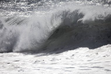 Büyük bir Atlantik dalgası Tazacorte sahiline çarpıyor. Beyaz köpük ve spreyle kırılan turkuaz suyun yakın çekimi denizin evcilleştirilmemiş gücünü gösteriyor. La Palma, Kanarya Adaları, İspanya