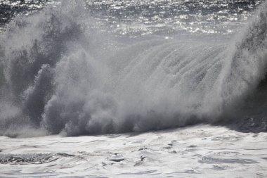 Büyük bir Atlantik dalgası Tazacorte sahiline çarpıyor. Beyaz köpük ve spreyle kırılan turkuaz suyun yakın çekimi denizin evcilleştirilmemiş gücünü gösteriyor. La Palma, Kanarya Adaları, İspanya