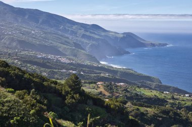 La Palma, Kanarya Adaları 'nın çarpıcı kıyı şeridi. Bereketli yeşil tepeler, geleneksel beyaz evler ve açık bir gökyüzünün altında mavi Atlantik Okyanusu 'yla buluşan sarp kayalıklar.