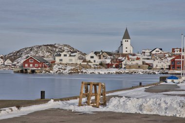 Skrhamn 'ın beyaz kilisesi renkli kıyı evleri ve donmuş limanın üzerinde yükseliyor. İsveç 'in batı kıyısından, Bohusln bölgesinden mükemmel bir kış kartı.