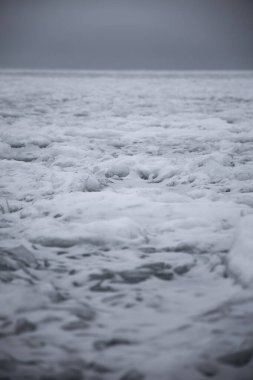 Ml, İsveç yakınlarındaki donmuş Vnern Gölü 'nün engin genişliği, bir adada soğuk, gri bir kış gökyüzünün altında ezilmiş buz ve kardan oluşmuş dokulu bir yüzeyi ve uzak bir deniz feneri barındırıyor.