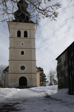 İsveç 'in Vrmland kentindeki tarihi Borgvik kilisesi (Borgviks kyrka) 1741 yılında inşa edilmiştir. Kar ve mavi gökyüzü olan bir kış mezarlığında beyaz taş mimarisi. Düşük açı görünümü.