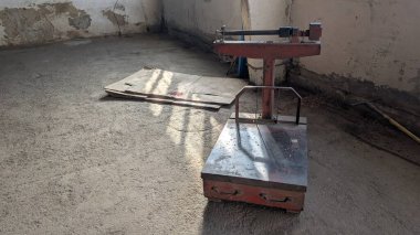 A vintage mechanical scale positioned on a dusty floor vividly showcases its age as well as the surrounding environment