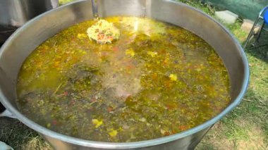 Gönüllü aşçı kepçeyle açık havada sebze çorbası, kırsal açık havada aşçı buharlı sebze çorbası servis ediyor.