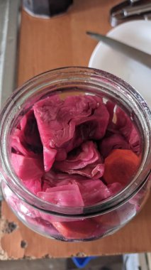 Kavanozda mayalanmış kırmızı lahana, ahşap masada keskin pembe salamura edilmiş mor dilimler, ev yapımı konserveler.