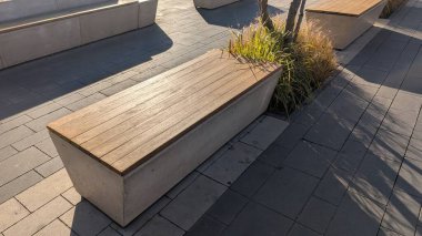 Yumuşak gün ışığıyla aydınlatılmış, sıcak ahşap kaplamalı beton tezgah, izole edilmiş oturma yeri sunuyor.