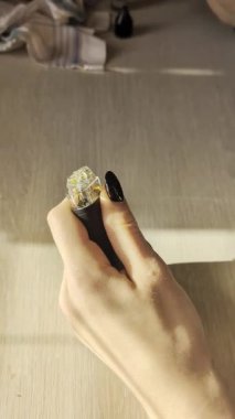 Kadın Elleri Cam Atomizer 'ı dolduruyor, sıcak güneş ışığı altında ahşap masa üzerinde, siyah çiviler ve sıkı sıkı kavrayış.,