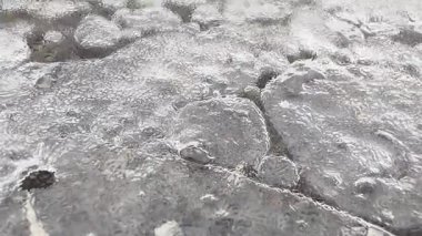 Buz kaplı asfalt, çıkıntılı sürgülü sert donmuş yüzey paslı cıvata, kaygan parıltı ve sıkışmış hava cepleri etrafında çatlamış.,