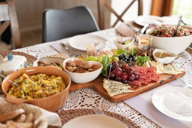 Öğle yemeği ya da kahvaltıda masada yemek için taze yiyecek. Soğuk tabak salata, peynir, jambon, üzüm ve zeytin. Evde peçeteyle hazırlanmış ev yapımı yemek. Pankart.