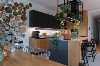 Lüks tarzda mutfak ve yemek odası, modern mobilyalar, sandalyeli ahşap tezgah. Duvarında şık bir tasarım ve dekorasyon olan kapalı bir mimari. Çağdaş dekoru olan akıllı ev.