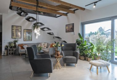 Penceresi ve şık merdivenleri olan modern oturma odası, beton zemin ve zarif lamba. Konforlu bir evde lüks bir oda. Emlak.