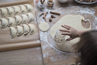 Geleneksel bir noel yemeği olarak mangır yoğuran bir kız. Nişasta ve ev yapımı yemek. Eller çemberi keser ve hamur tatlısı hazırlar. Üst görünüm.
