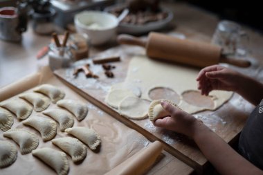 Geleneksel bir noel yemeği olarak mangır yoğuran bir kız. Nişasta ve ev yapımı yemek. Eller çemberi keser ve hamur tatlısı hazırlar. Üst görünüm.