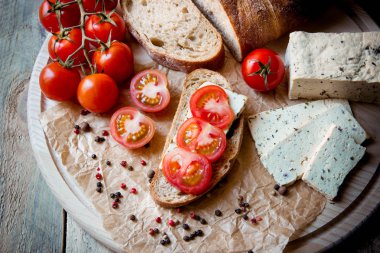 Rustik kahvaltı ev yapımı ekmek, domates, soya peyniri ve biber yuvarlak ahşap masa üzerinde dalı ile. Ülke kahvaltı konsepti