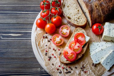 Rustik kahvaltı ev yapımı ekmek, domates, soya peyniri ve biber yuvarlak ahşap masa üzerinde dalı ile. Ülke kahvaltı konsepti