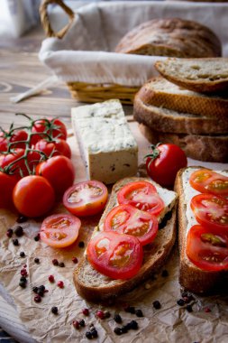 Rustik kahvaltı ev yapımı ekmek, domates, soya peyniri ve biber yuvarlak ahşap masa üzerinde dalı ile. Ülke kahvaltı konsepti