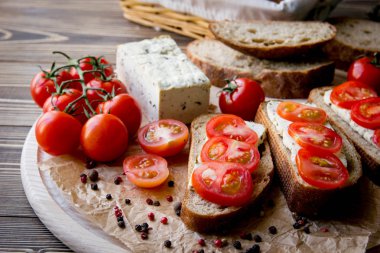 Rustik kahvaltı ev yapımı ekmek, domates, soya peyniri ve biber yuvarlak ahşap masa üzerinde dalı ile. Ülke kahvaltı konsepti