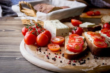Rustik kahvaltı ev yapımı ekmek, domates, soya peyniri ve biber yuvarlak ahşap masa üzerinde dalı ile. Ülke kahvaltı konsepti