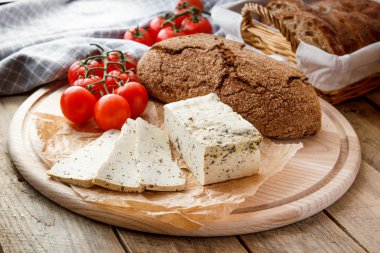 Rustik kahvaltı ev yapımı ekmek, domates, soya peyniri ve biber yuvarlak ahşap masa üzerinde dalı ile. Ülke kahvaltı konsepti