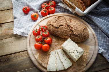 Rustik kahvaltı ev yapımı ekmek, domates, soya peyniri ve biber yuvarlak ahşap masa üzerinde dalı ile. Ülke kahvaltı konsepti