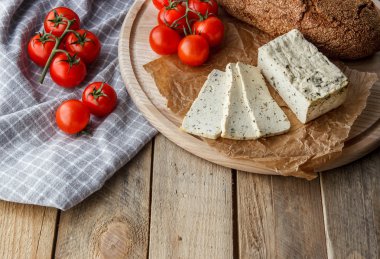 Rustik kahvaltı ev yapımı ekmek, domates, soya peyniri ve biber yuvarlak ahşap masa üzerinde dalı ile. Ülke kahvaltı konsepti