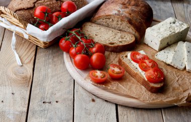 Rustik kahvaltı ev yapımı ekmek, domates, soya peyniri ve biber yuvarlak ahşap masa üzerinde dalı ile. Ülke kahvaltı konsepti