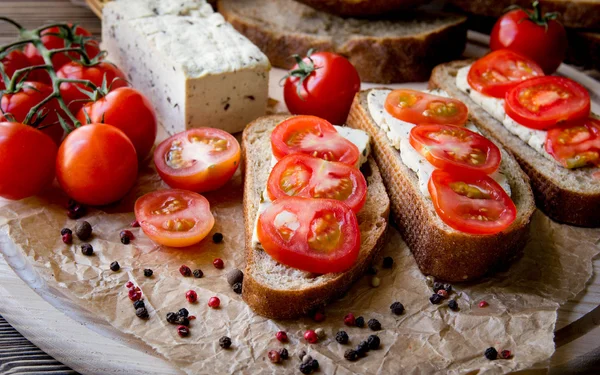 Rustik kahvaltı ev yapımı ekmek, domates, soya peyniri ve biber yuvarlak ahşap masa üzerinde dalı ile. Ülke kahvaltı konsepti