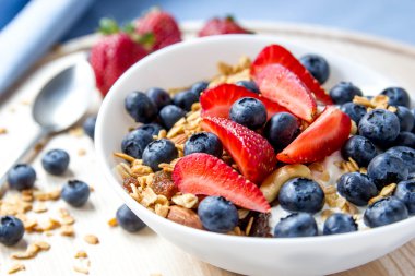 Sağlıklı kahvaltı kavramı. Granola yaban mersini ve beyaz kase çilek ile.