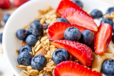 Sağlıklı kahvaltı kavramı. Granola yaban mersini ve beyaz kase çilek ile.