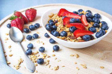 Sağlıklı kahvaltı kavramı. Granola yaban mersini ve beyaz kase çilek ile.