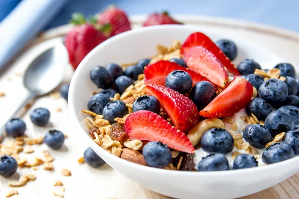 Sağlıklı kahvaltı kavramı. Granola yaban mersini ve beyaz kase çilek ile.