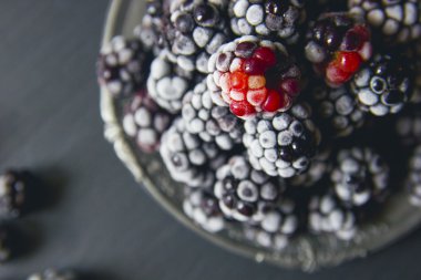 Siyah taş mutfak masası üzerinde taze donmuş böğürtlen