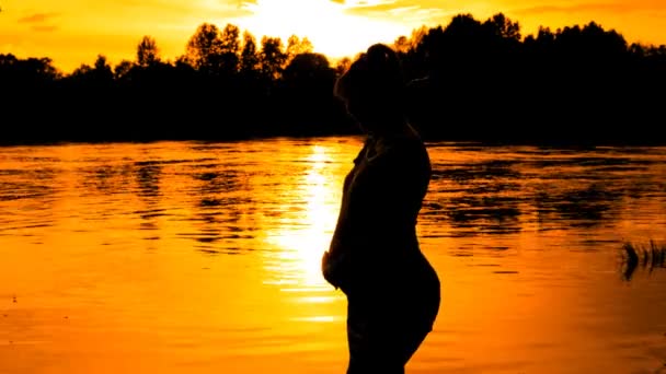 Gravid kvinna danser på sunset på floden bakgrund — Stockvideo