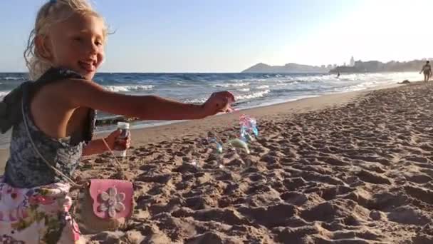 Criança sopra bolhas de sabão na praia — Vídeo de Stock