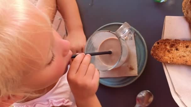 Kind maakt bubbels met stro in een glas. — Stockvideo