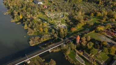 Hava görüntüsü Malbork Kalesi 'nin Malbork, Polonya' da olduğunu gösteriyor. Nogat Nehri 'nin solunda, karakola giden bir demiryolu köprüsü, konik bir kule, duvarlar ve sonbahar ışığı altında desenli bahçeler..