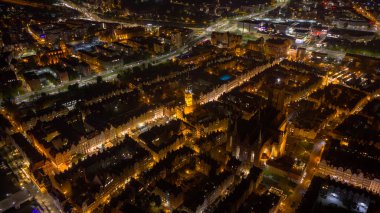 St. Marys Kilisesi, Main Town Hall saat kulesi, Long Market ve sıcak kehribar sokak lambalarıyla aydınlatılan Motlawa Nehri rıhtımı ile Polonya 'nın hava sahnesi..