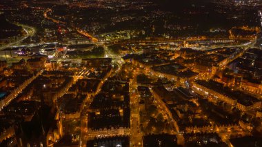 St. Marys Kilisesi, Motlawa Nehri, kanallar ve demiryolu hatları ile Polonya, Gdansk 'ın hava gece görüşü. Eski gengelli cepheleri modern yollarla kesişirken, uzun süreli trafik parlıyor.
