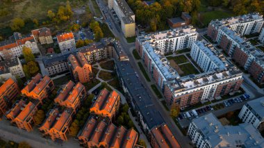 Altın Saatteki Gdansk yerleşim bölgesinin hava görüntüsü. Modern bloklar yeşil avluları, eski kırmızı kiremitli evleri dar sokaklar, arabalar ve ağaçlar görünür..