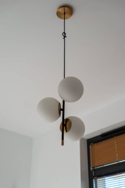 Polonya 'nın Gdansk kentindeki parlak beyaz bir odada, yumuşak doğal ışık panjurlarının yanında, ince siyah bir çubukta üç buzlu cam küre..