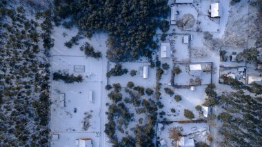 Polonya 'nın Nowy Lubiel kentinin yukarıdan görünüşü karla kaplı kır evleri, çitlerle çevrili araziler ve çam ormanının yanında ağaçlar, yumuşak mavi gölgeler oluşturan şeritler gösteriyor..